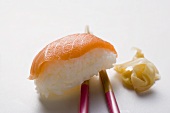 Nigiri sushi with salmon on chopsticks and preserved ginger