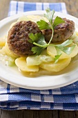 Burgers on potato and cucumber salad with parsley