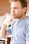 Junger Mann mit einem Glas Milch in der Hand