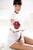 Young woman holding an apple on a plate
