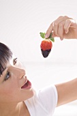 Young woman with a chocolate-dipped strawberry
