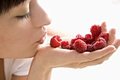 Young woman holding raspberries in her hand