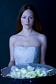 Red-haired woman holding a bowl of white rose petals