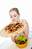 Young woman holding pizza on pizza board