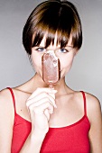 Young woman with a chocolate-covered ice cream on a stick