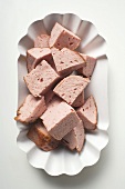 Diced Leberkäse (a type of meatloaf) in paper dish