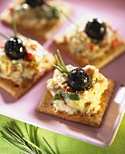 Crackers mit Auberginencreme und schwarzen Oliven