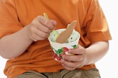 Junge isst Pfefferminzeis aus einem Becher