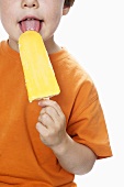 Junge isst gelbes Eis am Stiel