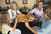 Familie im Restaurant teilt sich eine Pizza