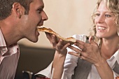 Frau füttert Mann mit Pizza im Restaurant