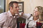 Woman in restaurant wiping man's chin