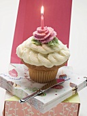 A cupcake with a birthday candle on a pile of napkins