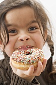 Girl holding a doughnut with sprinkles, partly eaten
