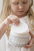Girl holding crocheted container of cosmetic pads