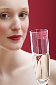 Young woman holding glass of sparkling wine with lipstick mark