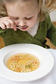 Small girl eating soup with teddy bear pasta