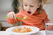 Kleines Mädchen isst Nudeln mit Tomatensauce und Parmesan