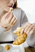 Young woman eating croissant