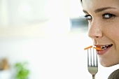 Young woman holding fork with carrot slices