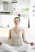 Young woman in yoga position on sofa