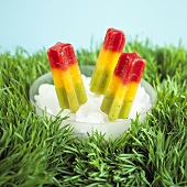 Coloured fruit ice lollies in a bowl of ice cubes