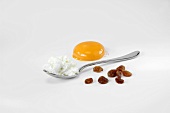 Baking ingredients (raisins, egg white on spoon & egg yolk)