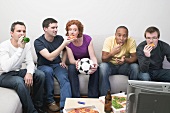 Friends sitting in front of TV with football, pizza & beer