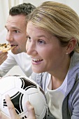 Young couple watching TV with football and pizza