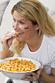 Young woman with German colours on her face eating snack food