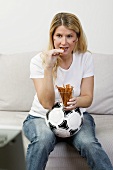 Young woman with German colours on her face eating salted sticks