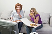 Zwei Freundinnen essen Pizza beim Fernsehen