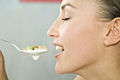Junge Frau isst Müsli mit Joghurt