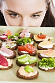 Young woman looking at tray of canapés