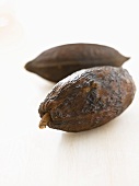 Two cacao fruits on white wooden surface