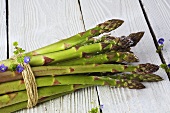 A bundle of green asparagus on white wood
