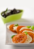 Tomatoes with mozzarella and basil and black olives