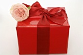 Gift in red wrapping paper with ribbon and rose