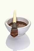 Chocolate mask in small bowl and on brush