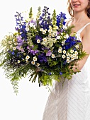 Woman holding bouquet of flowers (with delphiniums)
