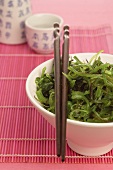 Seaweed salad with chopsticks, sake cup in background