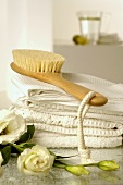 Handtücher und Massagebürste dekoriert mit Lisianthusblumen