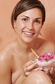 Woman holding bowl of bath salts and flower petals