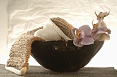 Massagegurt, herzförmige Seife und Orchideen in Holzschale