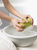 Woman squeezing out a sponge over a wash basin