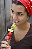 Young woman with fruit skewer