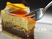 A piece of chocolate mango cream cake with fork