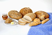A variety of breads and rolls with butter and marmalade