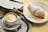 Caffe crema, a croissant and a sugar tin