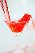 Red Martini being poured into a glass